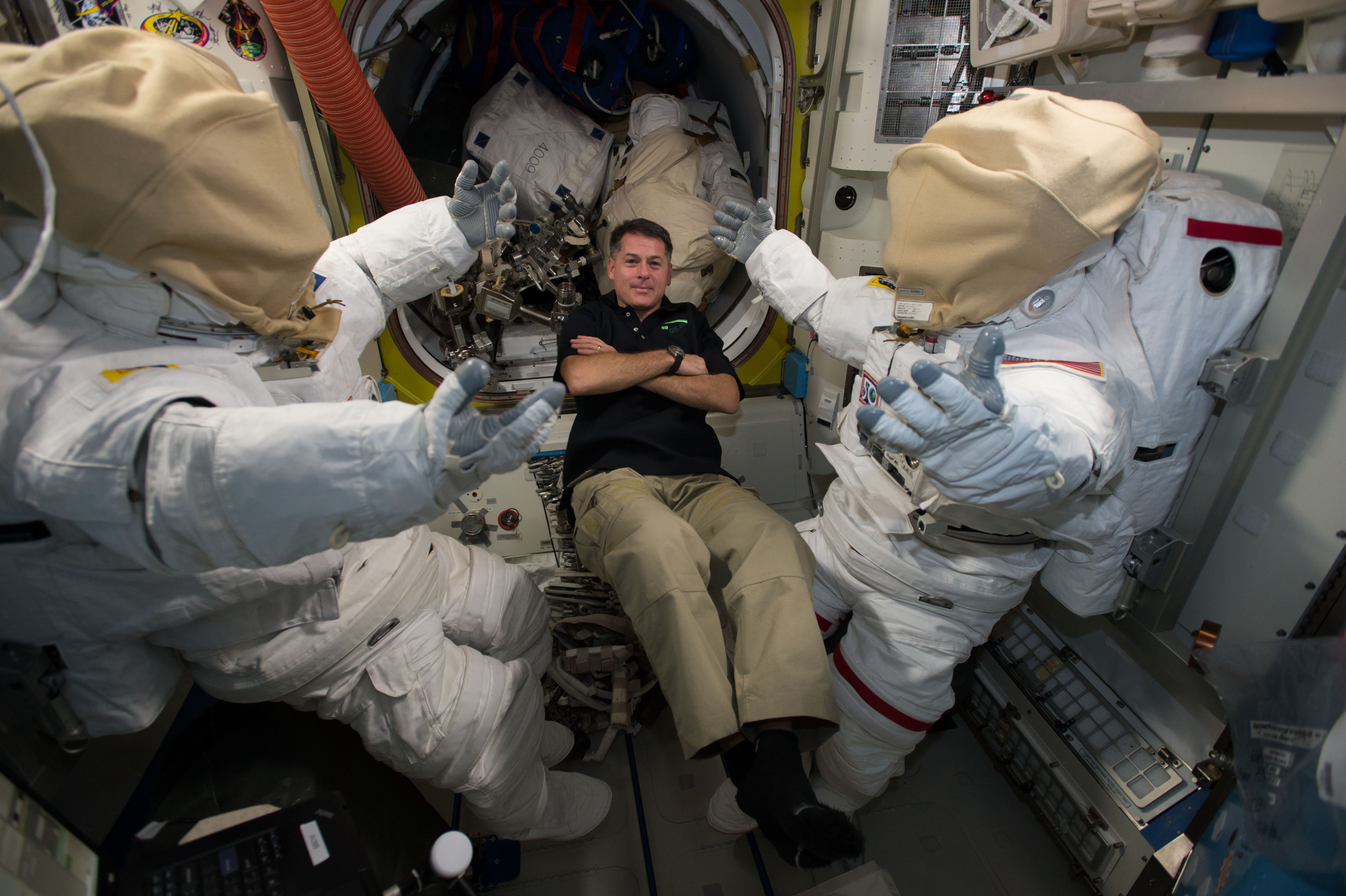 Deux combinaisons EMU suspendues dans le sas Quest de l'ISS